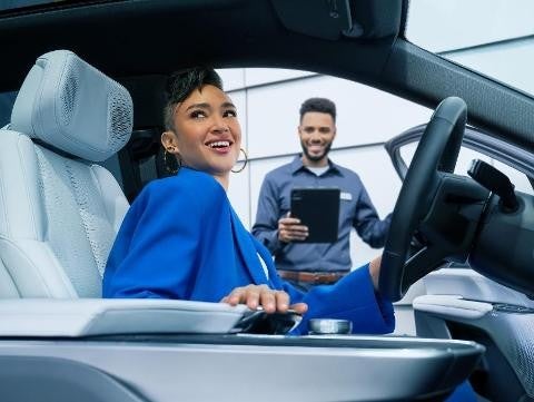 Bomnin Corvette in Miami FL service technician holding a car door open while holding a tablet and a woman sitting in the vehicle